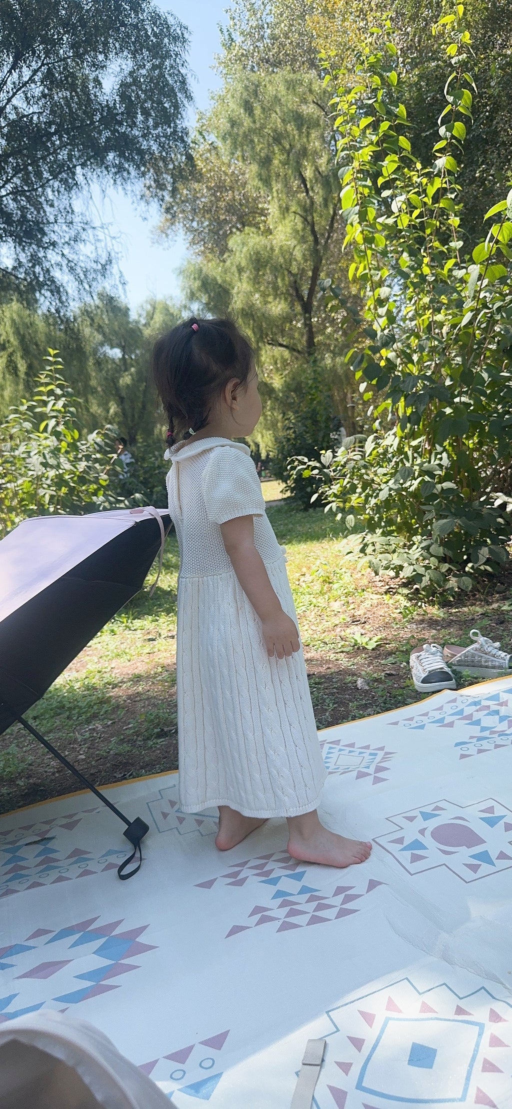 Child standing on the printed picnic mat outdoors
