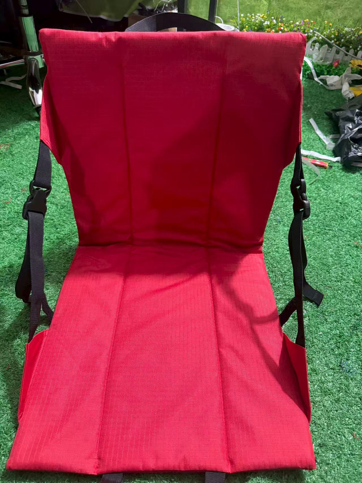 Red folding chair cushion with a padded backrest fitted to a folding chair