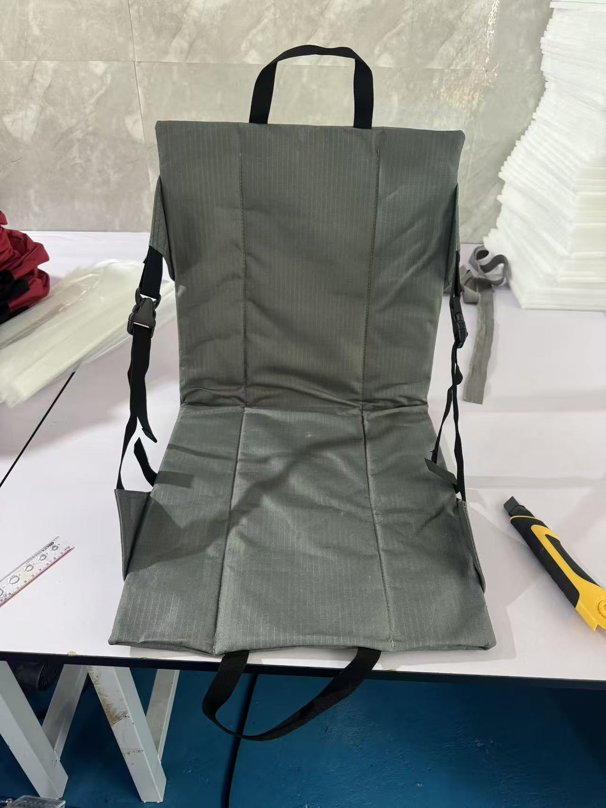Olive green folding chair cushion showing the oxford fabric weave and carry strap