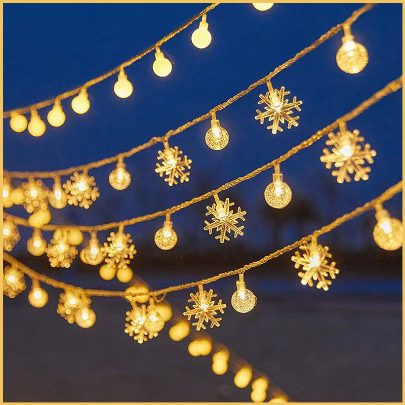 Snowflake and crystal ball solar string lights glowing warm white against a blue night sky