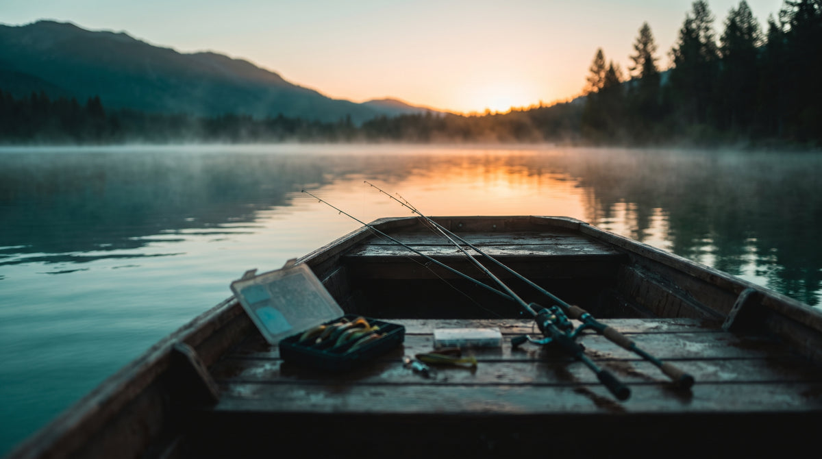 Dawn on a small lake, rods and a bait box on the boat deck