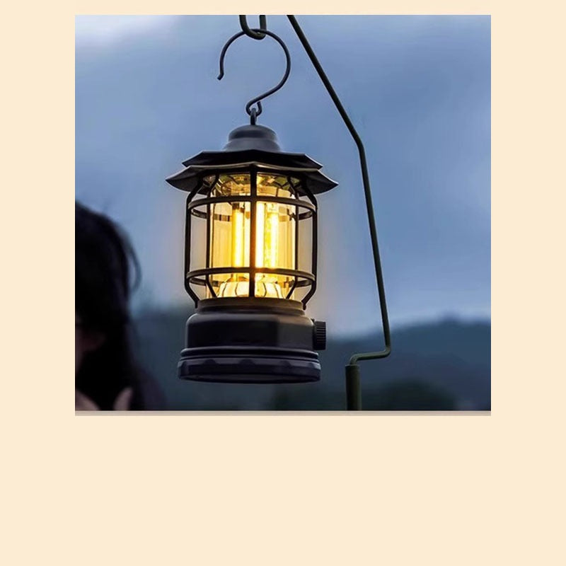 Retro camp lantern hanging from a hook and glowing warm yellow at dusk